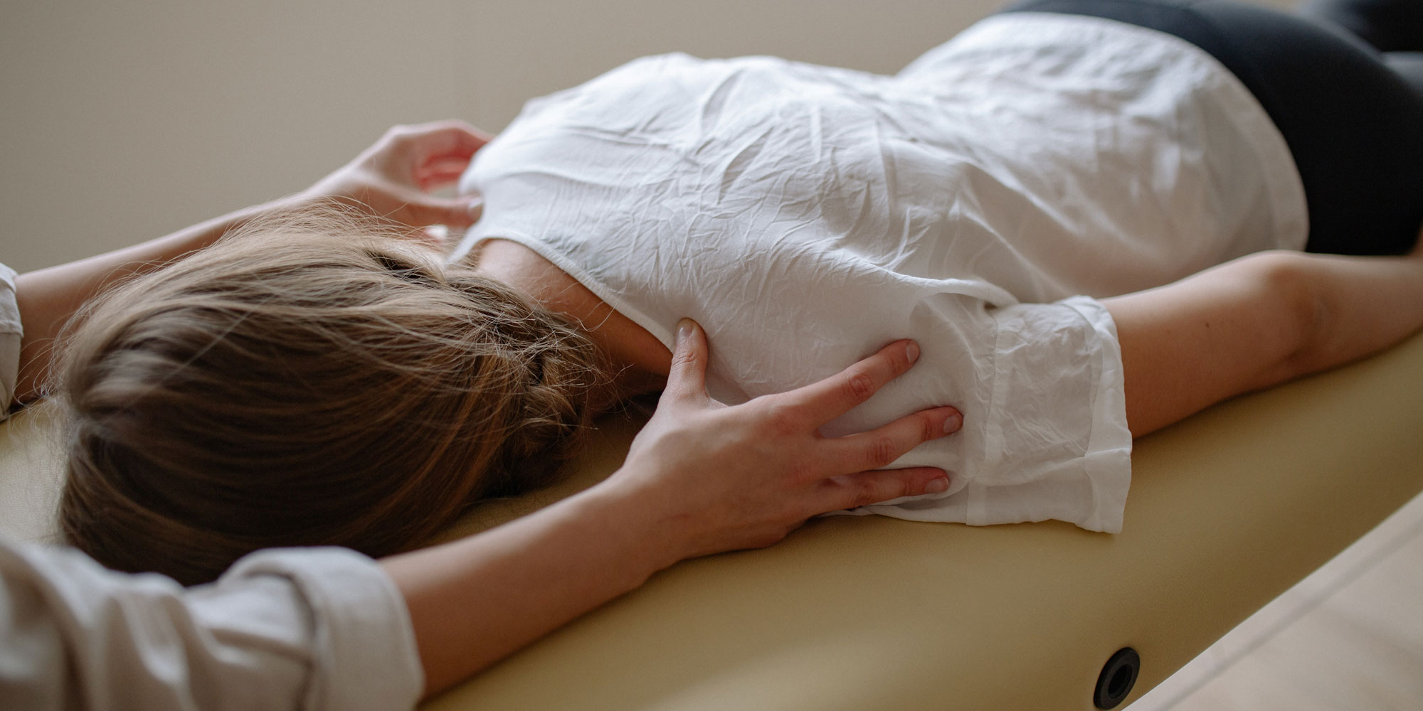 physiotherapist treating patient by manipulating shoulders
